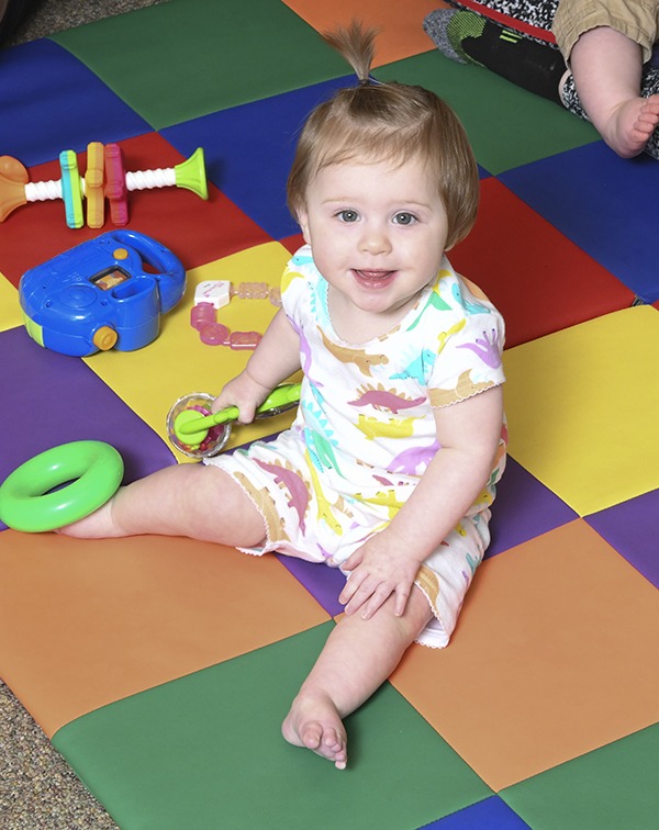 Baby girl sitting on colorful rug