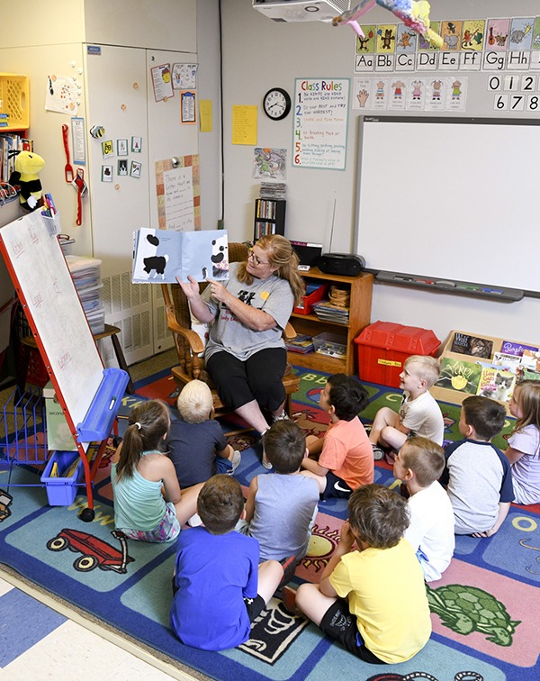 preschool kids gathered around as teacher reads outloud